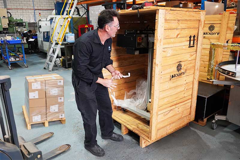 Image of a technician performing a routine inspection in an open-box warehouse, ensuring Packserv equipment is maintained to high standards.